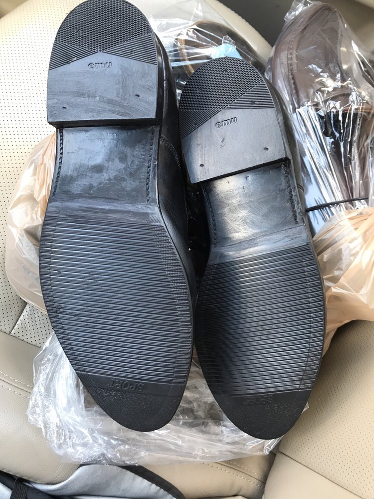 A pair of black leather dress shoes photographed sole-up, each with a new rubber half-sole and a new heel block.